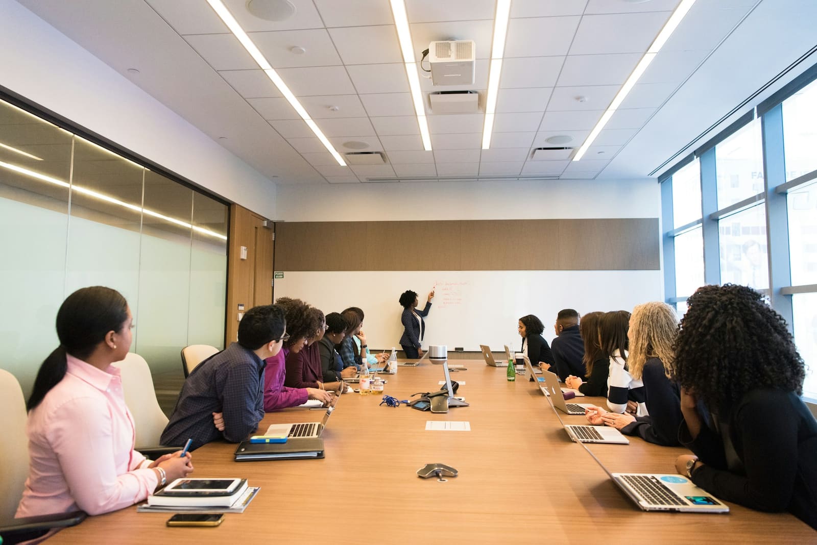 Une formatrice anime une session devant un groupe réuni autour d'une table de réunion